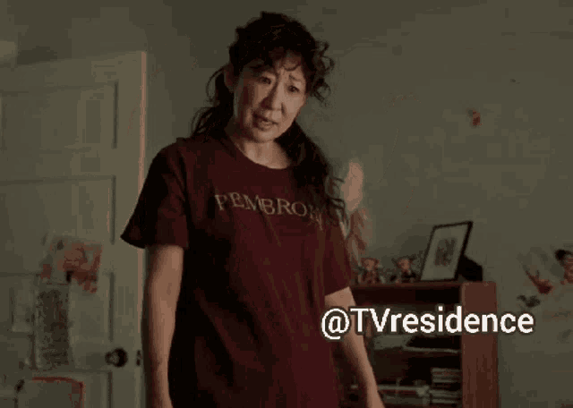 a woman wearing a t-shirt that says pembroke is dancing in a room with her arms outstretched .