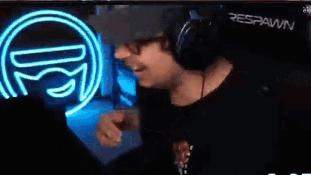 a man wearing headphones is smiling in front of a neon sign that says respawn .