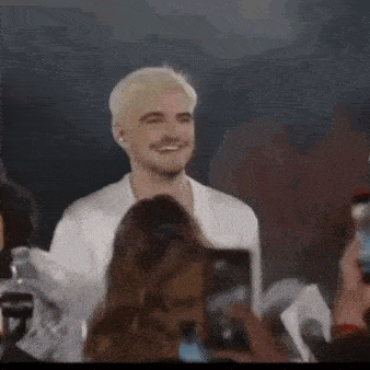 a man with blonde hair and a beard is standing in front of a crowd at a concert .