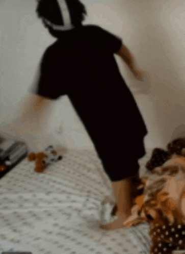 a person in a black shirt is standing on a bed .