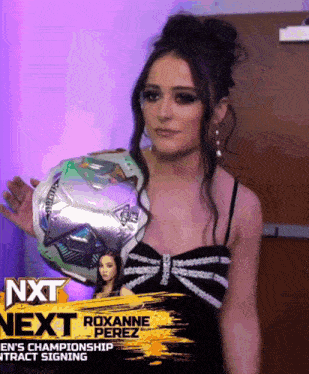 a woman in a black dress is holding a soccer ball in front of a sign that says next