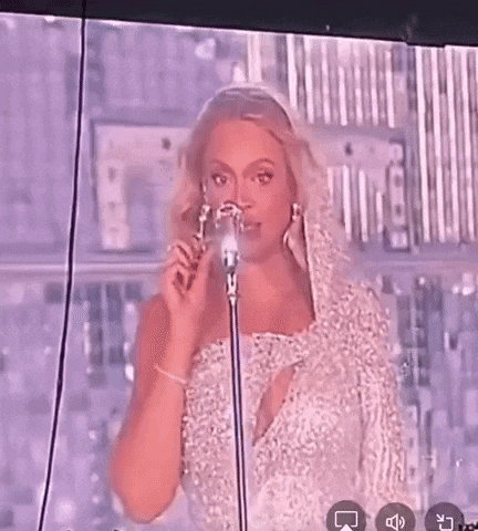 a woman in a white dress is standing in front of a microphone and a crowd .