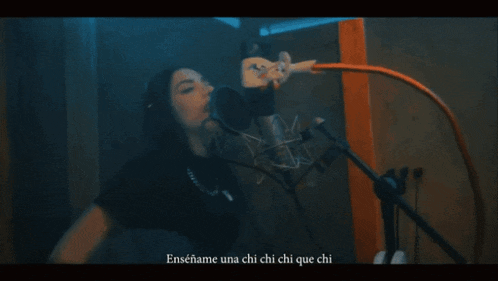 a woman singing into a microphone with the words " enseñame una chi chi que chi " written below her