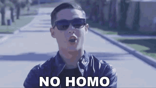 a man wearing sunglasses and a leather jacket is singing the song no homo .