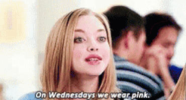 a woman is talking to a group of people while wearing pink .