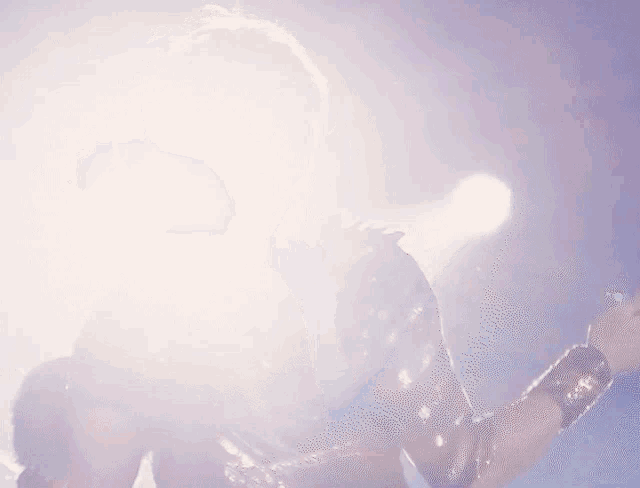 a man is playing a guitar in front of a purple light