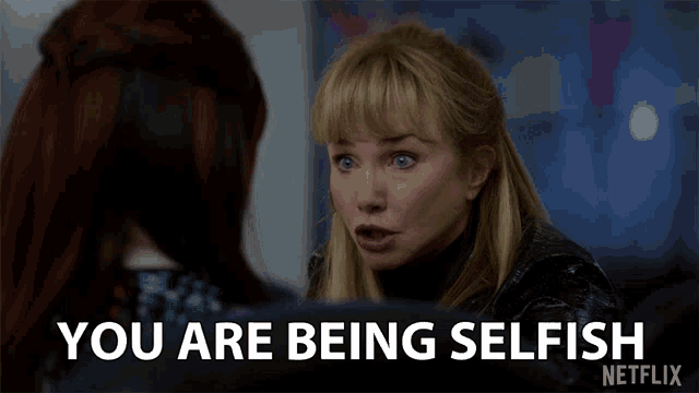 a woman talking to another woman with the words " you are being selfish " on the screen