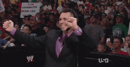 a man in a suit and tie is standing in front of a crowd with a sign that says john laurinatis more like