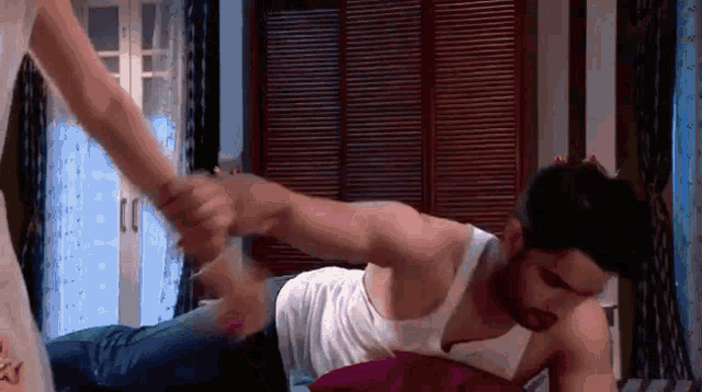 a woman is holding a man 's hand while he is laying on a bed