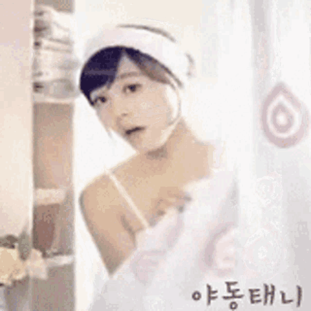a woman in a white tank top is standing in front of a shower curtain with korean writing on it