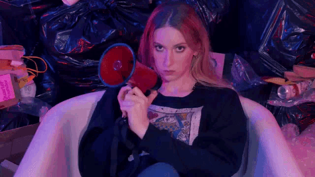 a young woman is sitting in a bathtub holding a megaphone .
