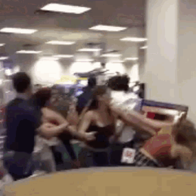 a group of people are standing in a room and fighting .