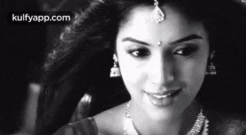a black and white photo of a woman wearing a necklace and earrings