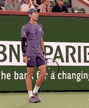 a man holding a tennis racket in front of a bn parie sign