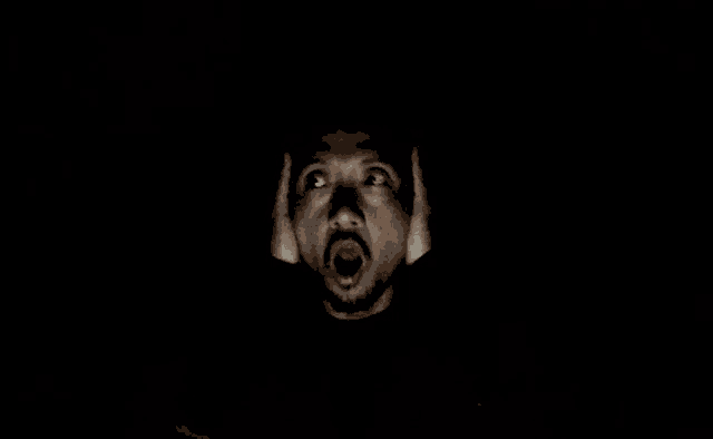 a man with his mouth open is covering his ears with his hands