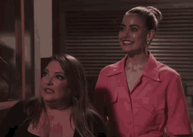two women standing next to each other one in a pink shirt