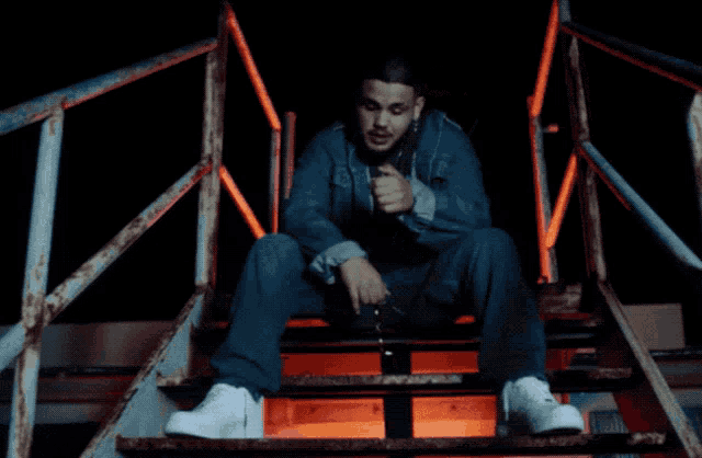 a man in a denim jacket sits on a set of steps