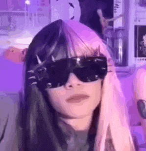 a girl with pink and black hair is wearing sunglasses and a purple background .
