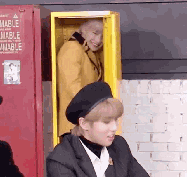 a man in a yellow jacket and black beret is standing next to a man in a black beret .
