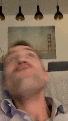 a man is making a face in front of a painting of the golden gate bridge