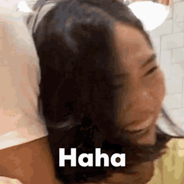 a woman is laughing while holding another woman 's head and the words `` haha '' are above her head .