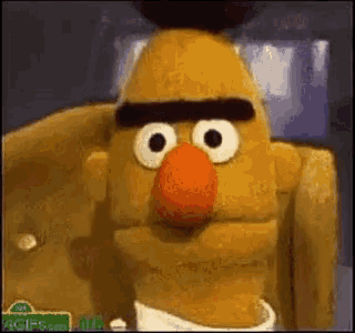 bert from sesame street is wearing a white shirt and a tie .