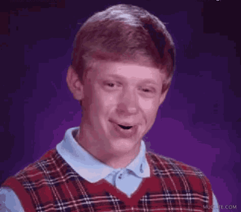 a man wearing a plaid vest and a blue shirt is making a funny face .