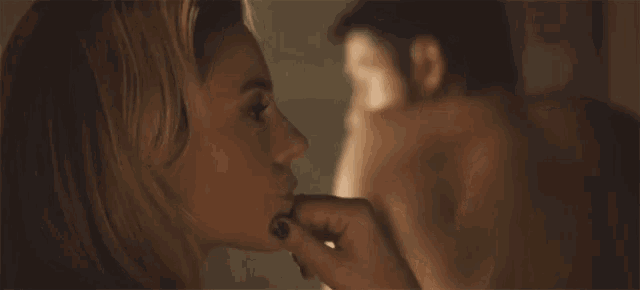 a woman is touching a man 's face in a close up of a movie scene .