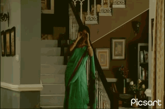 a woman in a green sari is standing on a set of stairs with picsart written in the corner