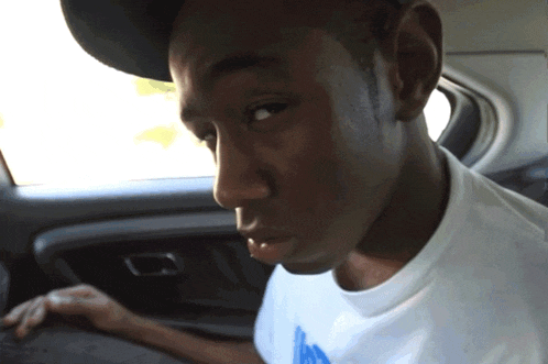 a young man wearing a hat and a white t-shirt with a blue s on it