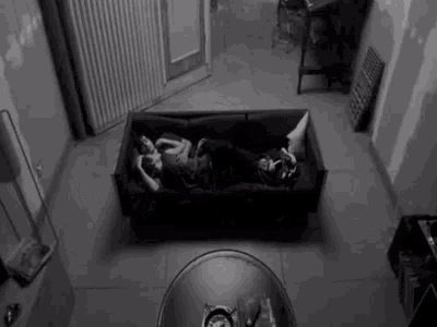 two people are laying on a black couch in a room .