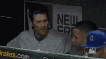 two baseball players are standing next to each other in the dugout .