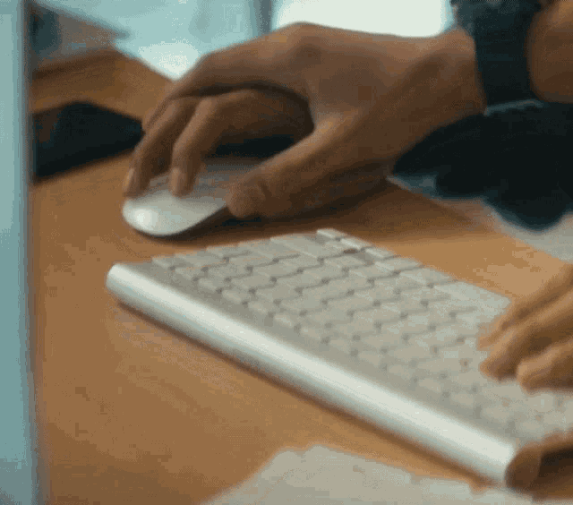 a person is typing on a keyboard with a mouse in the background