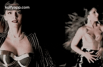 a woman with a very large breast is dancing in a black background .