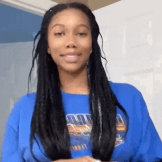 a woman with braids is wearing a blue shirt and a blue sweater .