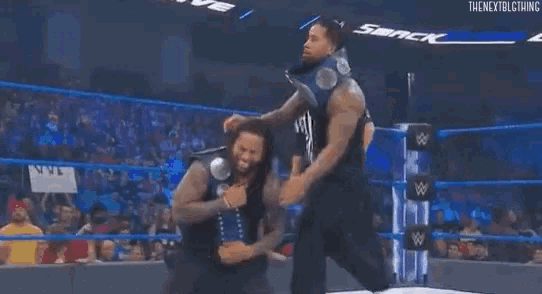 a man is carrying another man on his shoulders in a wrestling ring .