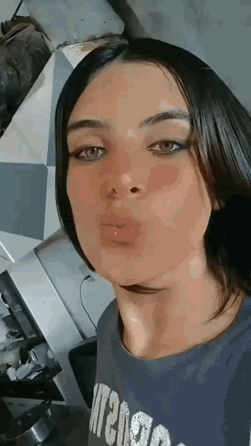 a woman is blowing a kiss at the camera while wearing a blue shirt .