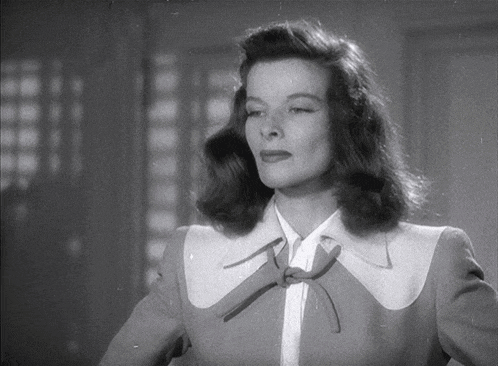 a black and white photo of a woman with a bow on her shirt