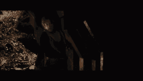 a man is standing in a dark room with a pile of coins on the floor