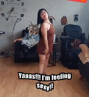 a woman is standing in front of a couch with a cat on her back and the caption yaaas i 'm feeling sexy