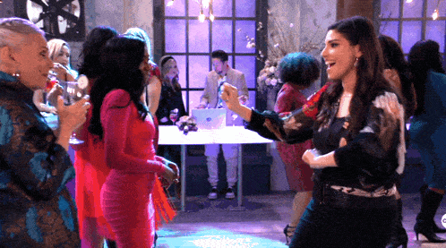 a group of women are dancing in a room with a laptop on the table