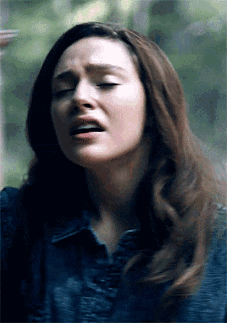 a woman in a blue shirt is making a funny face