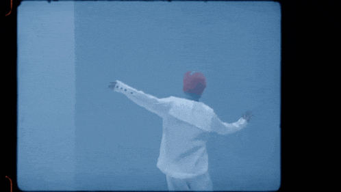 a man in a white shirt and red hat stands in front of a blue background