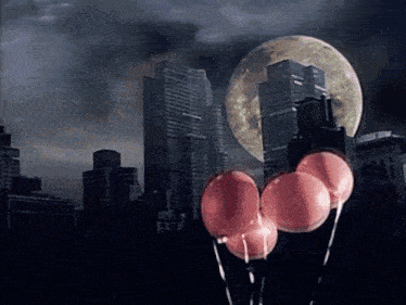 a bunch of pink balloons are floating in the air in front of a city skyline