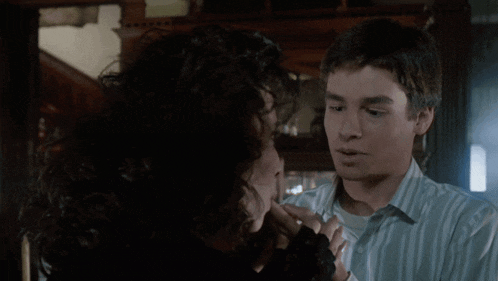 a man and a woman are looking at each other and the woman is touching the man 's face