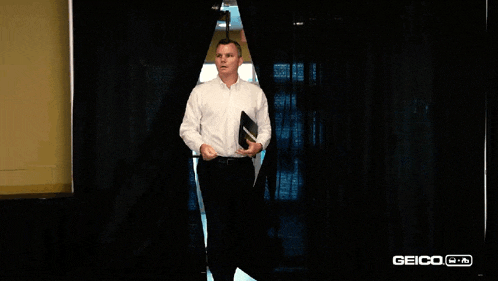 a man in a white shirt is standing in front of a black curtain with a sign that says exit