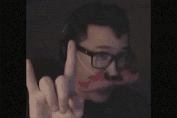 a man wearing glasses and a fake mustache is making a middle finger sign .