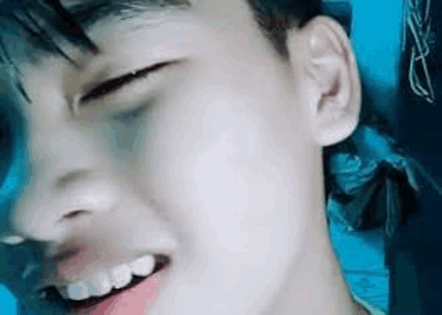 a close up of a boy 's face with his eyes closed and his mouth open .
