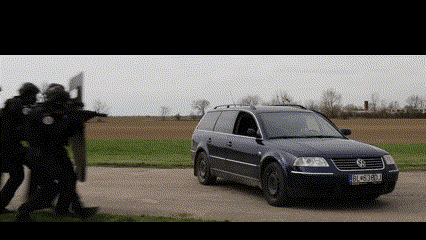 a group of police officers are standing in front of a blue volkswagen station wagon