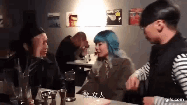 a group of people are sitting at a table talking to each other in a restaurant .